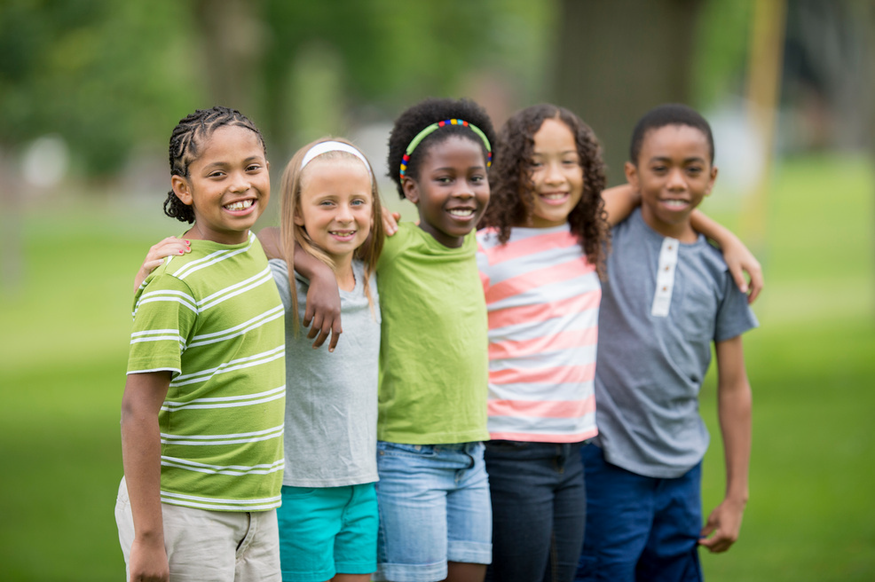 group of children standing in a line holding their hands behind ech other's backs