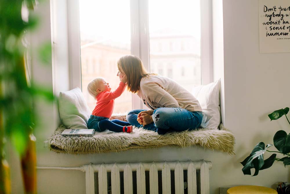woman playing with child in window