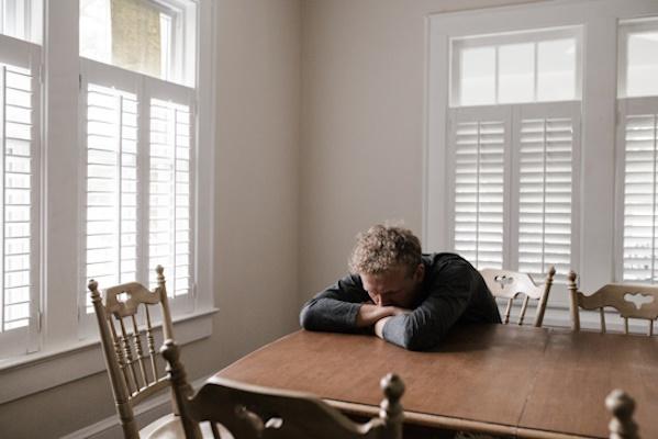 Your health and wellbeing young man sitting at table distressed and unhappy