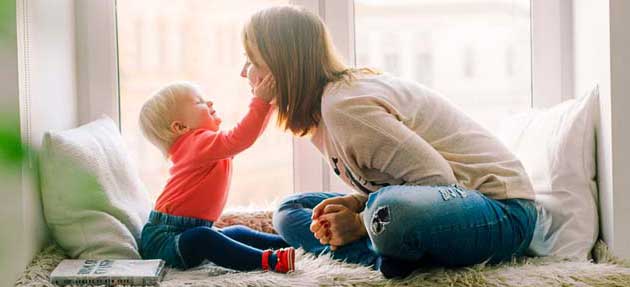 woman and child sitting in a window smiling and playing